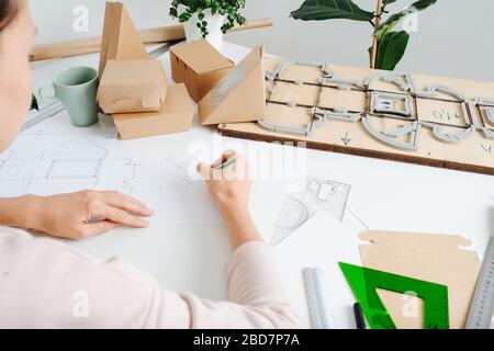 Nahaufnahme eines Kastenherstellers, der hinter einem Schreibtisch von hinten arbeitet. Stockfoto