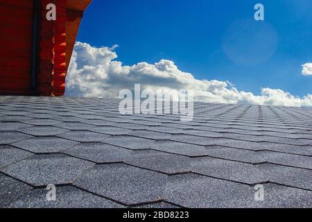 Graues weiches Dach auf dem Dach des Hauses. Wolkiger blauer Himmel im Hintergrund Stockfoto
