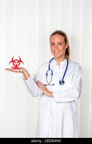 Weibliche Ärztin, die ein Schild mit biologischer Gefährdung in der Hand hält Stockfoto