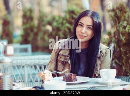 Frau glücklich essen. Nahaufnahme Portrait schön lächelnd leicht multikulturelle Mädchen Student Blick auf Sie Kamera Essen Eis Schokolade Dessert Co Stockfoto