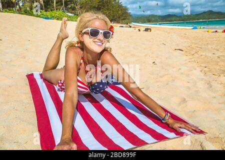 Sonnenbändchenschild während der Covid-19-Pandemie. Weißes Gesicht für die Verwendung einer sanitären Maske für Frauen mit amerikanischem Flaggentuch im hawaiischen Lanikai Beach, mit Stockfoto