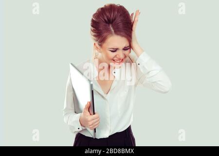Wütende wütende Geschäftsfrau hält Computer, schreiende Hand auf dem Kopf isoliert hellgrünen Hintergrund. Negative menschliche Emotionen, Gesichtsausdrücke, Gebühr Stockfoto