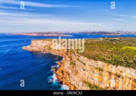 Heller blauer pazifischer Ozean und Himmel über Sandsteinfedern am Eingang zum Hafen von Sydney in erhöhter Luftansicht, die die Stadt CBD überragt. Stockfoto