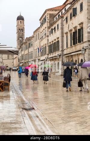 Touristen mit Sonnenschirmen, zu Fuß, durch die Straßen der Altstadt, Dubrovnik im Regen. Stockfoto