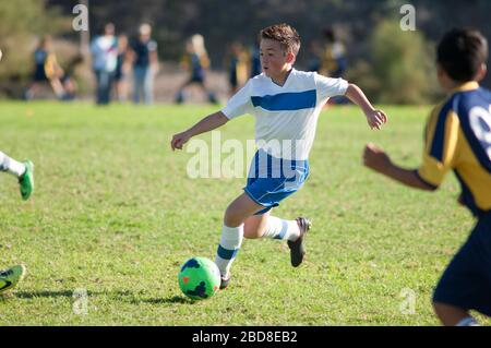 Jugendlicher Fußballspieler dribbelte Ball durch Verteidiger Stockfoto