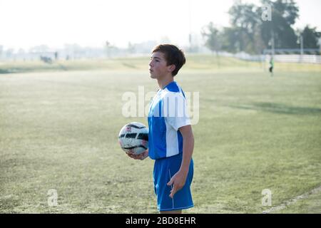 Teen Fußballspieler hält Ball und bereit für einen Wurf in Stockfoto