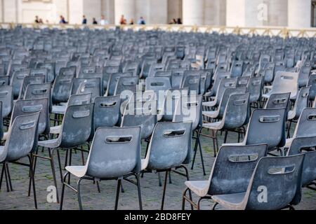 Leere Reihen grauer Kunststoffstühle am Petersplatz, Vatikanstadt, Rom, Italien. Stockfoto