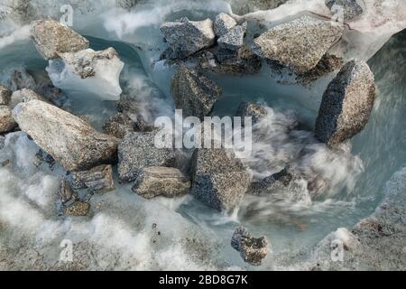 Glazialer Schmelzwasserstrom mit Felsbrocken, die sich auf der Oberfläche des Snowbird-Gletschers, der Talkeetna Mountains, Alaska, ablagern. Stockfoto