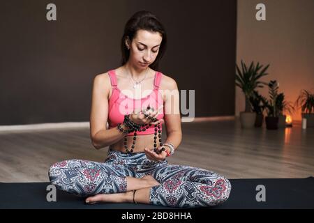 Junge Frau meditiert allein mit einem Yoga-Studio für Yoga mit Perlen Stockfoto