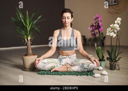 Frau, die Meditation im Yoga-Studio in der Mitte der Blumen macht Stockfoto