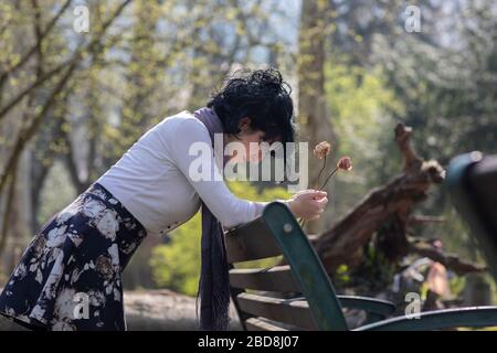 Eine Frau in Trauer, die die Arme auf einer Parkbank hält Stockfoto