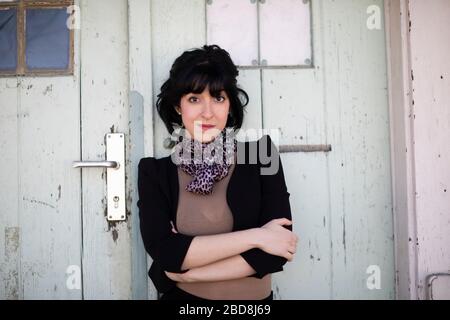 Junge Frau mit schwarzen Haaren vor einer Tür Stockfoto