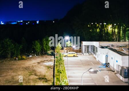 Bukarest, Rumänien - 30. April 2012: Nachtstadtszene Schwenk-Shift-Objektivfokus Antenne über dem hinteren Parkplatz des Restaurantgebäudes mit Licht von Bukarest im Hintergrund Stockfoto