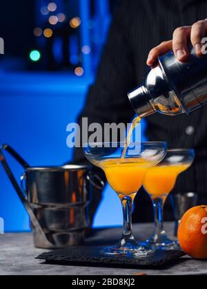 Der Kellner in der Bar bereitet einen Cocktail mit Orangensaft und Wodka für einen Kunden zu Stockfoto