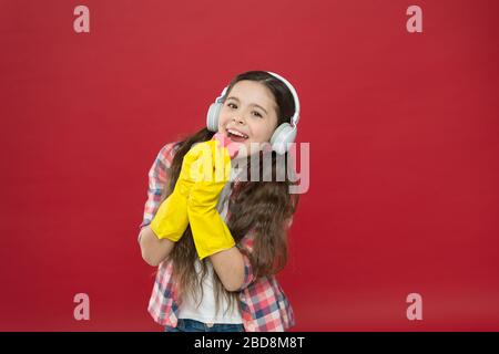 Machen Sie den Haushalt freudiger. Harmlose Reiniger mit einfachen Zutaten. Reinigungsparty. Mädchen tragen zur Reinigung Kopfhörer und Schutzhandschuhe. Musik hören und reinigen. Viel Spaß. Stockfoto