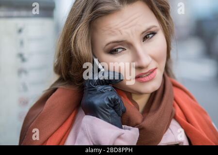 Schlechte Nachrichten. Traurige Frau am Telefon. Nahaufnahme Portrait Kopfschuss von wunderschönem verärgerter, ernsthafter Mädchen-Student spricht über mobile Stadtbild Outdoor-Backgroun Stockfoto