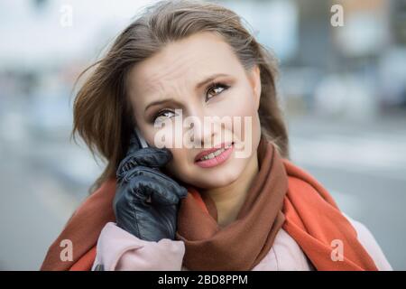 Schlechte Nachrichten. Traurige Frau am Telefon. Nahaufnahme Portrait Kopfschuss von wunderschönem verärgerter, ernsthafter Mädchen-Student spricht über mobile Stadtbild Outdoor-Backgroun Stockfoto