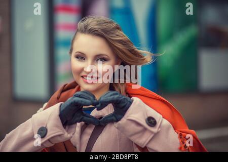 Liebe. Closeup Portrait lächelnd glückliche junge Frau, die Herzen Zeichen, Symbol mit Händen isolierte Stadt scape Hintergrund. Positive menschliche Emotion expressio Stockfoto