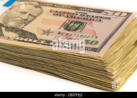 Stapel amerikanischer Dollar mit einer Rechnung von 50 Dollar oben isoliert auf einem weißen Hintergrund. Stockfoto