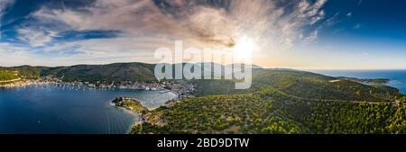 Luftaufnahme des Jachthafens Vis bei Sonnenuntergang, Kroatien, viele chaotisch stehende Boote in einer Bucht, Dächer von oranger Farbe, Sonnenschein, Hügel mit grünen Bäumen Stockfoto