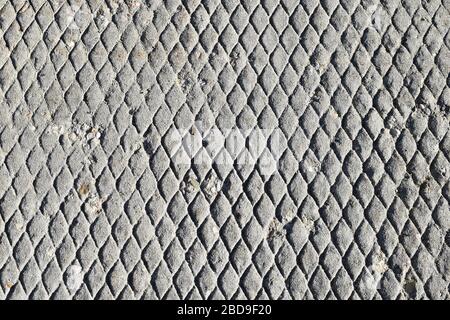 Verwitterter und gealterter Gehwegbeton mit rautengemusterter Textur. Stockfoto