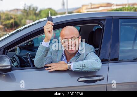 Junger gutaussehender Geschäftsleute, der die Schlüssel seines neuen Autos zeigt. Stockfoto