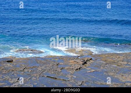 Blick auf eine Felsplattform oder ein Regal und das Meer mit kleinen Wellen. Stockfoto