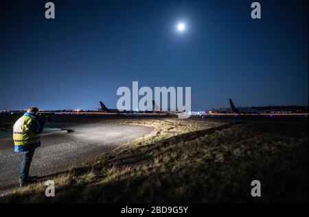 08. April 2020, Hessen, Frankfurt am Main: Der Vollmond überstrahlt vorübergehend stillgelegte Lufthansa-Flugzeuge am Frankfurter Flughafen. Wegen der Corona-Pandemie hat die Lufthansa einen Großteil ihrer Flotte vorübergehend außer Dienst gestellt. Foto: Boris Roessler / dpa Stockfoto