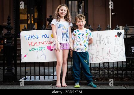 Brooklyn, Vereinigte Staaten Von Amerika. April 2020. Held und Aeson, die vom Brooklyn Methodist Hospital in Park Slope leben, posieren vor ihren Zeichen, die den Mitarbeitern des Gesundheitswesens am 7. April 2020 in Brooklyn, New York danken. (Foto von Gabriele Holtermann-Gorden/Sipa USA) Credit: SIPA USA/Alamy Live News Stockfoto