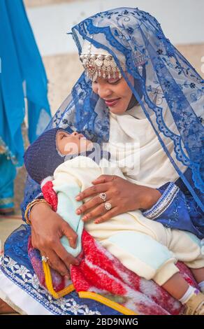 Eine omanische Mutter im traditionellen Kleid mit ihrem Baby in Muscat im Sultanat Oman. Stockfoto