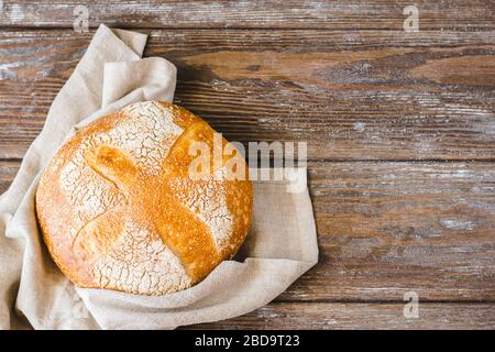 Ein Brötchen mit frisch gebackenem, heeastless Brot mit rustikalem Hintergrund. Das Konzept der hausgemachten Diät-Bäckerei ohne Hefe. Stockfoto