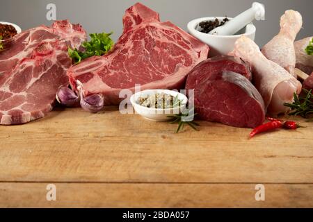 Eine Auswahl an verschiedenen rohen Gourmet-Fleisch auf einem rustikalen Holzhackbrett. Stockfoto