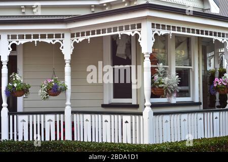 Detail der weißen Vintage Villa Veranda mit Schiefer Zaun und Blumentöpfen hängen von der Decke. Stockfoto