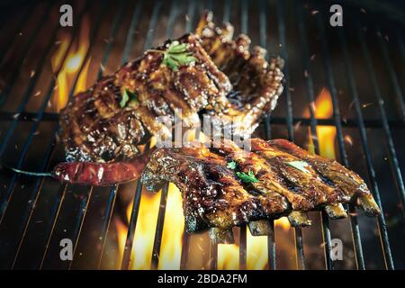 Klebrig würzig marinierte Schweinefleischrippen grillen auf einem Grill über den heißen, flammenden Kohlen in Nahaufnahme Stockfoto