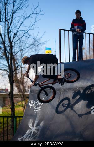 Lemberg, Ukraine - 12. März 2020: Junger Mann, der Tricks auf einem BMX-Fahrrad macht. BMX im Skatepark der Stadt. Teenager fahren mit dem Fahrrad in einem urbanen Bike- und Skatepark Stockfoto