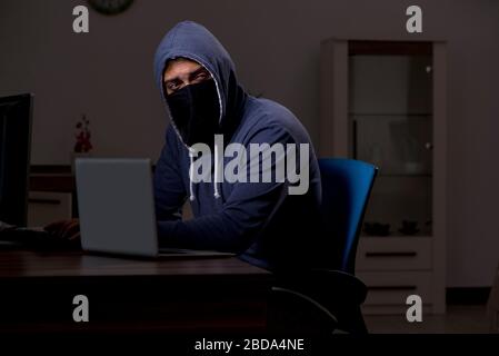 Ein Hacker, der die Sicherheitsfirewall spät im Büro hackt Stockfoto