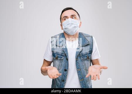 Mann in einer Atemmaske, die auf eine Kamera blickt, die italienische Geste zeigt, das heißt, was Sie wollen, auf weißem Hintergrund. Stockfoto