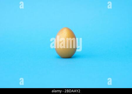 Ein goldenes osterei auf blauem Pastellgrund. Osterkonzept. Platz für Text. Stockfoto