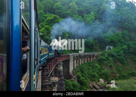 Schöne Aussicht auf die grüne Landschaft und Puffing und Rauchen Dampfmaschine über eine Brücke mit dem Nilgiri Mountain Railway Train, Tamil Nadu Stockfoto