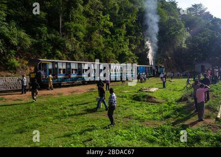 Passagiere steigen aus dem Zug für eine kurze Pause an einer der Halts auf Nilgiri Mountain Railway, Tamil Nadu, Indien Stockfoto