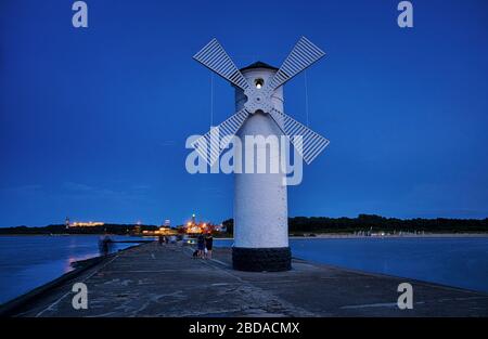 Leuchtturm mit Touristen an der Ostsee mit Windmühlenflügeln in Swinemünde. Swinoujscie, Polen Stockfoto