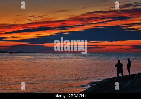 Zwei Angler an der Ostsee bei Sonnenuntergang. Stockfoto