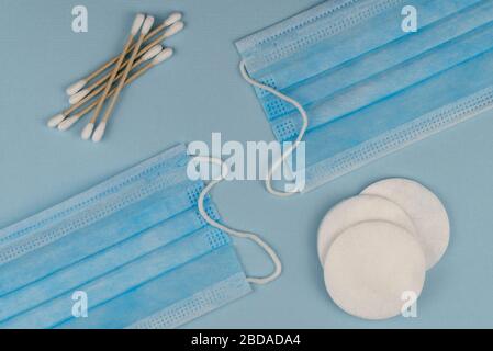 Flache Laienzusammensetzung mit medizinischer Maske und natürlichen Baumwollstäbchen auf blauem Hintergrund. Stockfoto