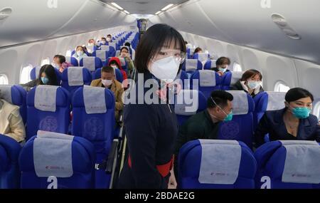 Wuhan, Chinas Provinz Hubei. April 2020. Ein Flugbegleiter, der eine Gesichtsmaske und eine Schutzbrille trägt, dient Passagieren an Bord des Flugs MU2527 von China Eastern Airlines auf dem Tianhe International Airport in Wuhan, der zentralen chinesischen Provinz Hubei, am 8. April 2020. Wuhan hob am Mittwoch die Beschränkungen für ausgehende Reisen auf, nach fast 11 Wochen Sperrzeit, um die Verbreitung von COVID-19 zu beschränken. Credit: Cheng Min/Xinhua/Alamy Live News Stockfoto