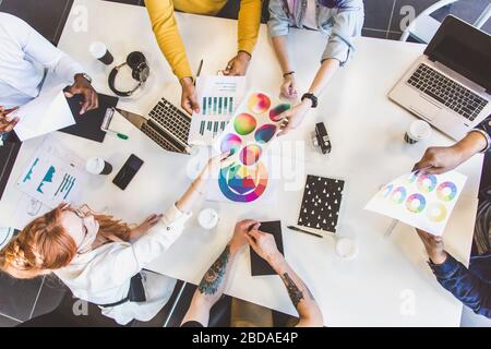 Gruppe von Führungskräften aus mehreren ethnischen Gruppen, die während eines Meetings diskutieren. Business man und Frau sitzen am Tisch im Büro und lächeln. Ein Team junger Leute Stockfoto