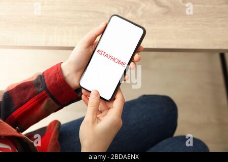Frau, die Telefon mit Hashtag hält, bleibt zu Hause. Quarantänekonzept Stockfoto