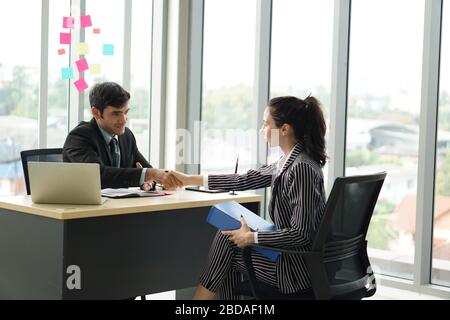 Junge Arbeitgeber in schwarzen Anzügen schütteln die Hände während eines Treffens im Büro. Angenehme Atmosphäre nach einem Vorstellungsgespräch. Stockfoto