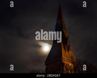 England North Yorkshire Knaresborough Vollrosafarbener Mond hinter der Lichtwolke in der Holy Trinity Kirche spire Dienstag, 7. April 2020 Stockfoto