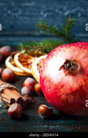 Früchte Granatapfel, Nüsse, Zimtstangen und getrocknete Orangenscheiben. Weihnachten. Selektiver Fokus Stockfoto