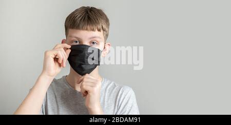 Junger Mann, der eine schwarze Operationsmaske trägt, um sich vor dem Virus Covid 19 zu schützen. Isoliert. Leerzeichen für Text. Prävention von Coronavirus. Stockfoto